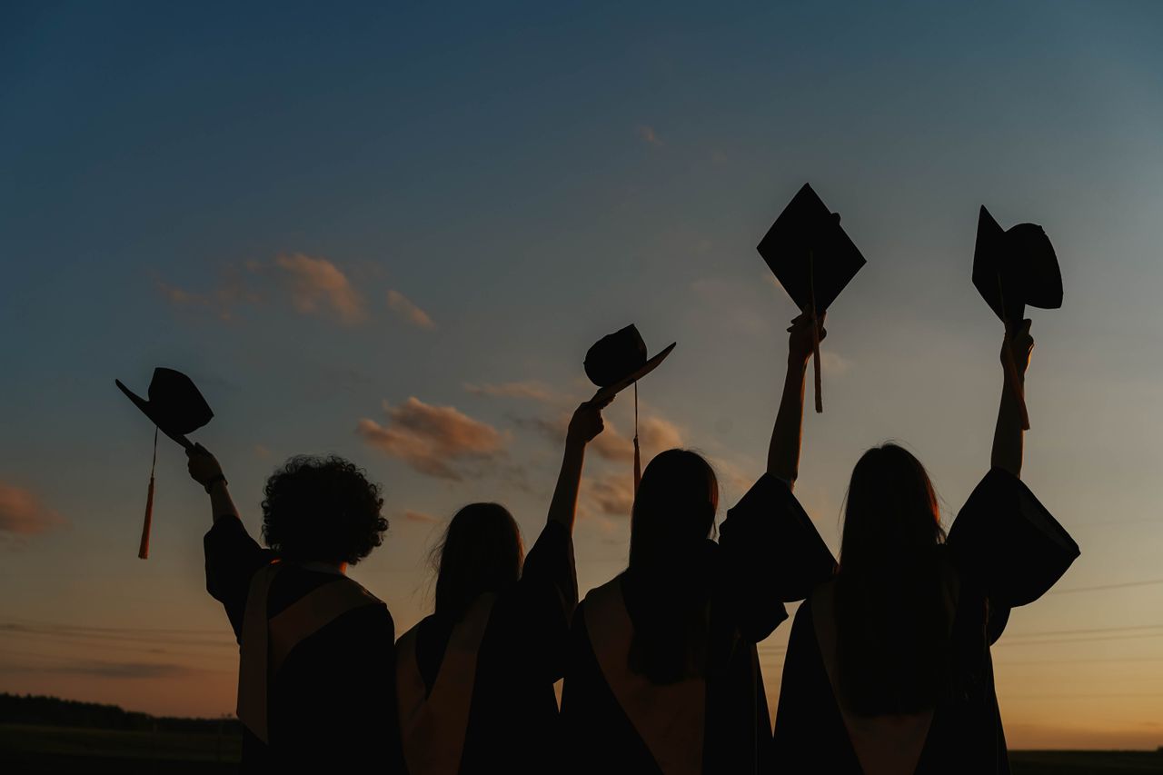 service-06 Silhouette of graduates raising caps in joy at sunset.